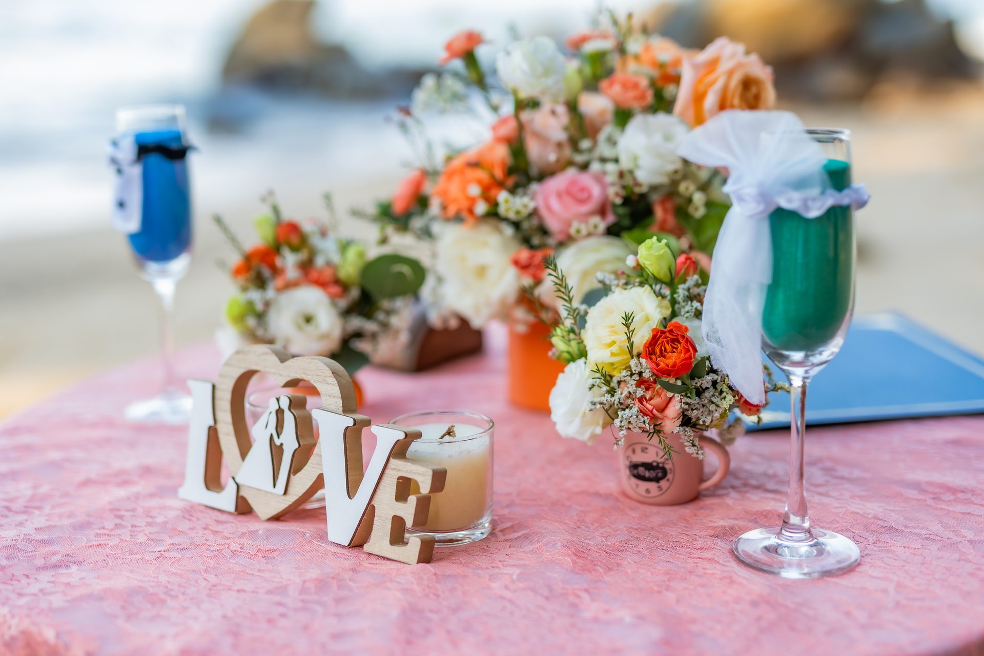 Champagne flutes, a Love sign and fresh florals styled on a signing table beside the sea Champagne flutes, a Love sign and fresh florals styled on a signing table beside the sea
