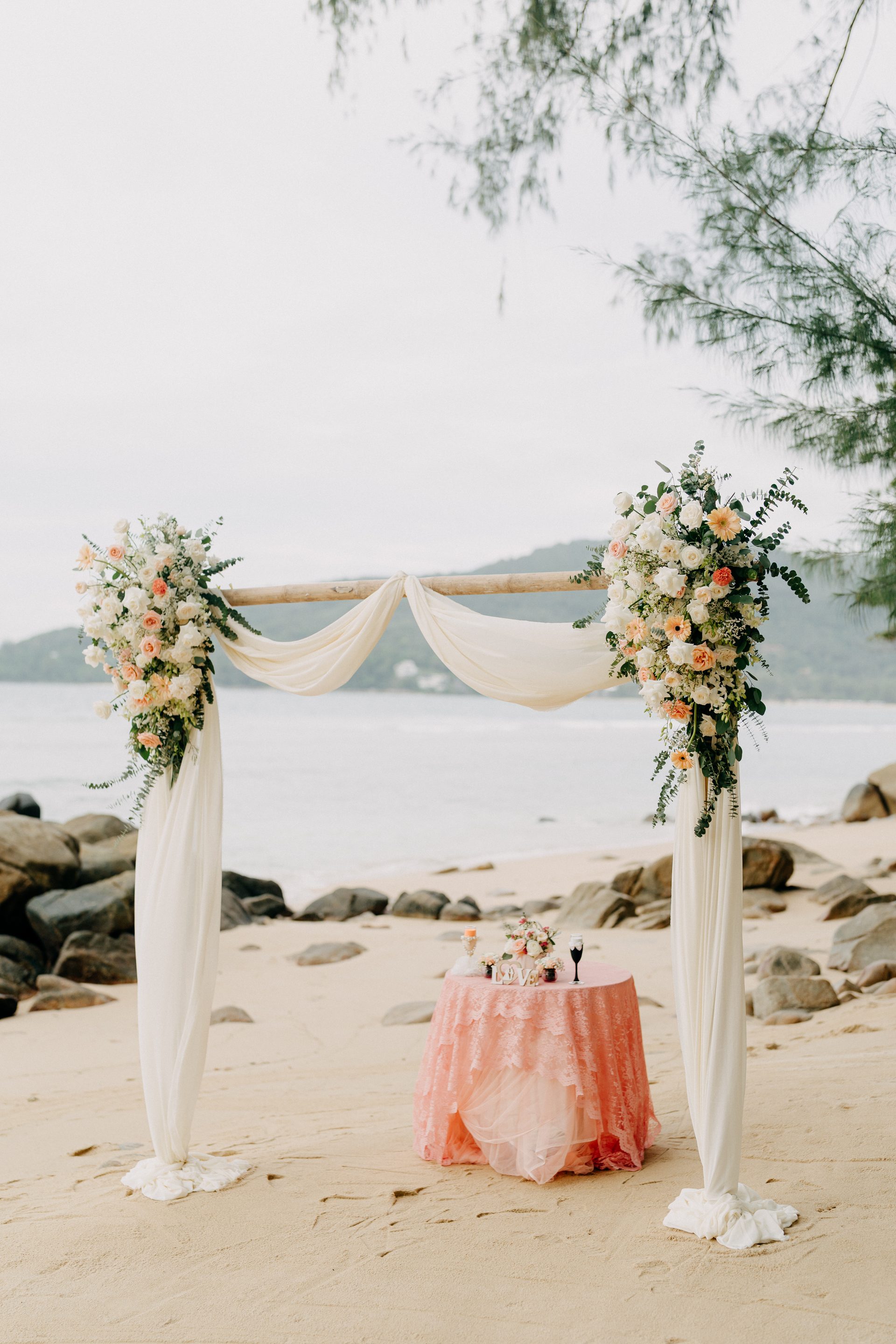 Pastel floral arch and signing table framed by the sea at Hua Beach