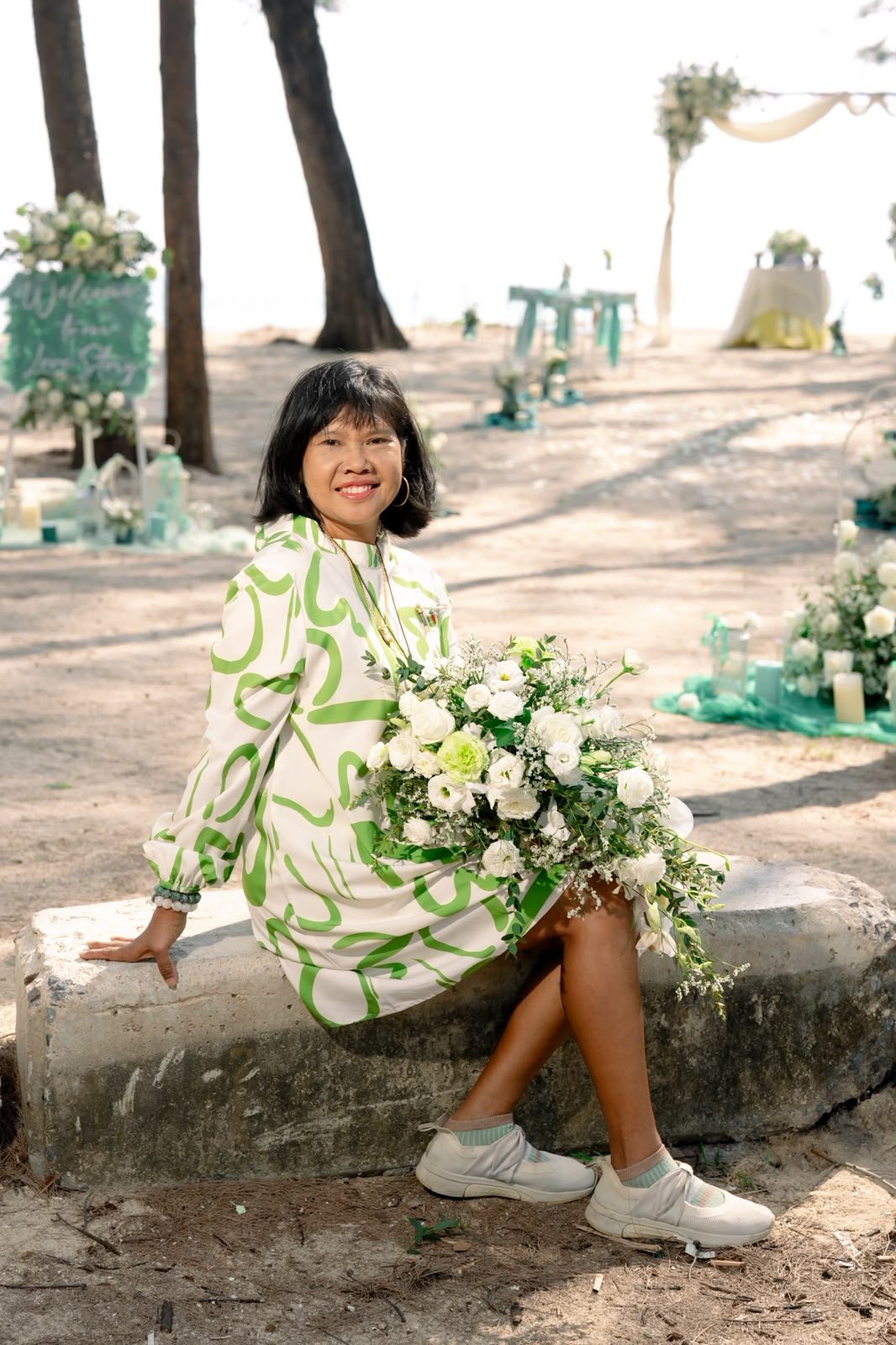 Supparin taking a quiet moment beside the ceremony florals before a Barefoot wedding